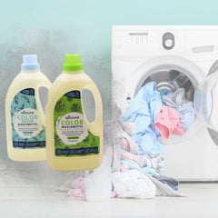 Flaschen des oecolife Color Waschmittel Limette und Sensitiv vor einer Waschmaschine mit Wäsche